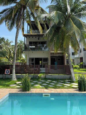 A two-story building with a swimming pool in front. - Serenity Beach Annex (Kokrobite)