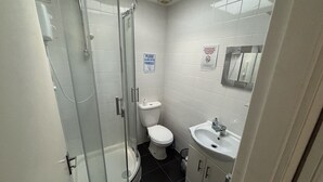 A bathroom with a glass-enclosed shower, a toilet, and a sink. - Gassiot House (London)