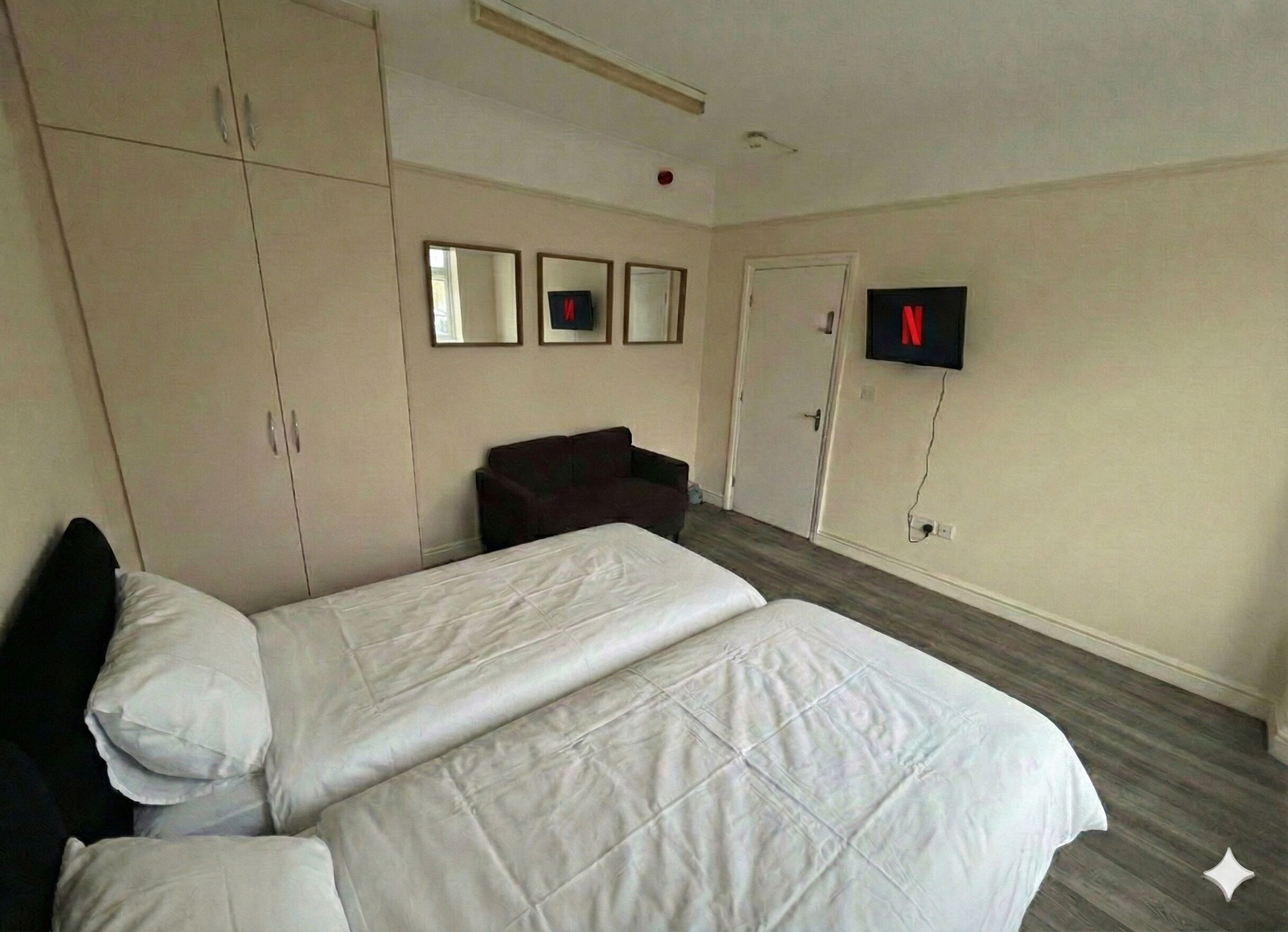 Una camera d'albergo con due letti, un armadio, una televisione e una porta.