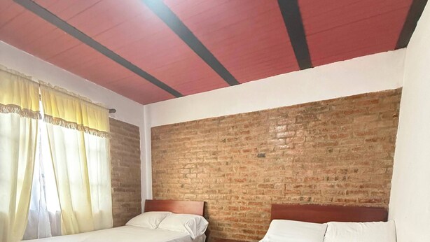 Een kamer met twee bedden, een bakstenen muur en een houten plafond.