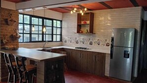 Een keuken met een centraal eiland, houten kasten, een roestvrijstalen koelkast en een raam met uitzicht.