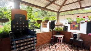 A covered outdoor area with a wooden floor, a weighing scale, and hanging plants.