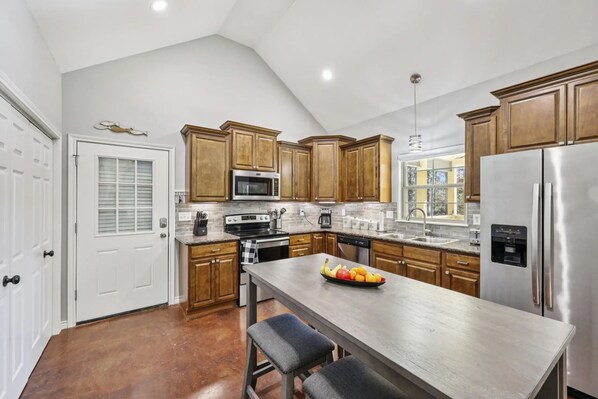A modern kitchen with wooden cabinets, stainless steel appliances, and a central island with seating.