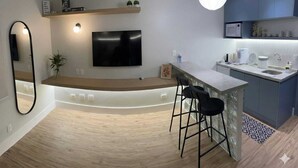 Una cocina moderna con microondas integrado, un lavamanos y una barra con taburetes.