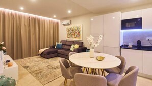 Uma sala de estar moderna com um sofá, uma mesa de jantar redonda e uma cozinha com micro-ondas.