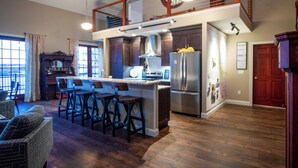 A spacious kitchen with a central island, bar stools, and a high ceiling with exposed beams.