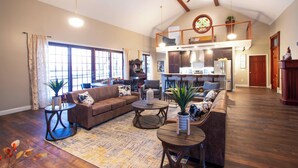 A spacious living area with a high ceiling, wooden floors, and a cozy seating arrangement.