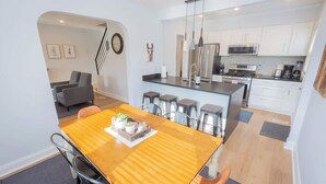 A modern kitchen with white cabinets, stainless steel appliances, and a central island with bar stools. - Charming Single Family Home - Free 3 car parking (Washington)