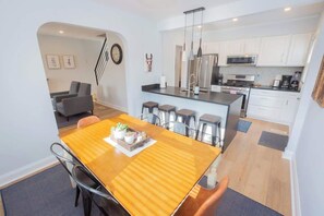 A modern kitchen with white cabinets, stainless steel appliances, and a central island with bar stools. - Charming Single Family Home - Free 3 car parking (Washington)