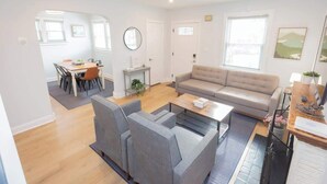 A modern living room with a sofa, chairs, a coffee table, and a dining area with a table and chairs. - Charming Single Family Home - Free 3 car parking (Washington)