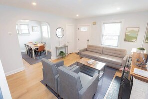 A modern living room with a sofa, chairs, a coffee table, and a dining area with a table and chairs. - Charming Single Family Home - Free 3 car parking (Washington)