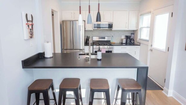 A modern kitchen with a central island, bar stools, stainless steel appliances, and pendant lighting. - Charming Single Family Home - Free 3 car parking (Washington)