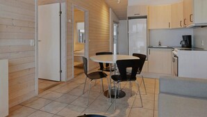 Una cocina moderna con comedor, paredes de madera y un refrigerador blanco.
