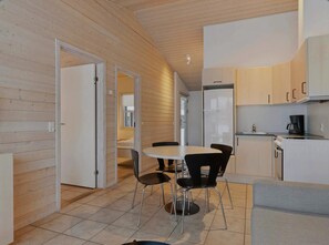 Una cocina moderna con comedor, paredes de madera y un refrigerador blanco.