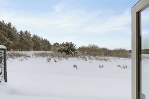 A snowy landscape with a tree and a building in the background. - Ideal holiday apartment for active relaxation (Pandrup)