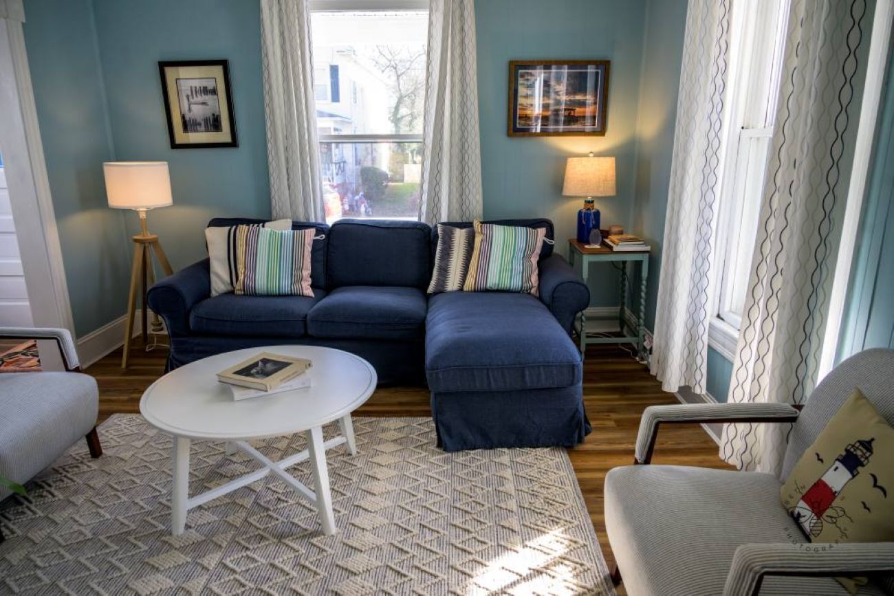 Ein Wohnzimmer mit einem blauen Sofa, einem weißen Couchtisch und einem gemusterten Teppich.