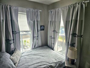 A bedroom with a bed, curtains, a window, and a picture on the wall. - Lovely Newly Renovated 3 Bed House Walk to IronMan with Off-Street Parking (Cambridge)
