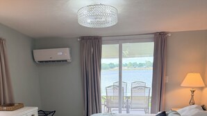 Une chambre d’hôtel avec un lit, un bureau, une chaise, une lampe et une vue sur un lac.
