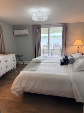 A hotel room with a bed, a desk, a chair, a lamp, and a view of a lake. - Renovated Lakefront Luxury Retreat by Legoland (Haines City)
