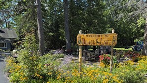 Un panneau d’accueil indiquant l’entrée du lac Black, entouré d’un jardin agrémenté de fleurs jaunes et de rochers.
