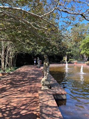 A garden with a statue, a fountain, and a brick pathway. - Masters Week Golf Estate / 6BR / Sleeps 12 / Fire Pit & Outdoor Living (Aiken)