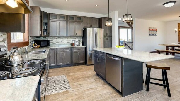 A modern kitchen with a central island, stainless steel appliances, and a view to the living area. - Grand 8-Bedroom Retreat, 7 Baths - Perfect Chalet (The Blue Mountains)