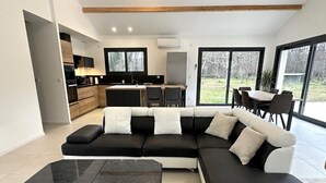 Un saló modern amb un sofà modular, una taula de café negra i una cuina al fons.