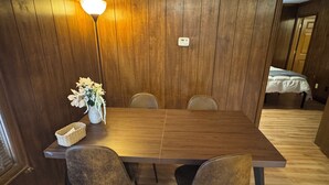 A wooden dining table with four chairs, a vase with flowers, and a lamp. - Prime 1BR: Minutes to Toledo, Sylvania & MI (Toledo)