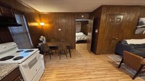 A compact kitchen with a stove, dining table, and chairs. There is a bed in the adjacent room. - Prime 1BR: Minutes to Toledo, Sylvania & MI (Toledo)