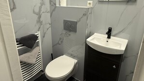 Casa de banho compacta com sanita, lavatório e suporte para toalhas.