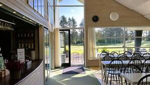 Ein Restaurant mit Barbereich, Außenbereich und großen Fenstern mit Blick auf einen Golfplatz.