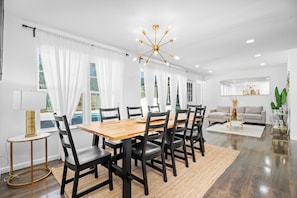 A spacious dining area with a wooden table and black chairs, a modern chandelier, and a living area with a sofa and a coffee table. - Relaxed Luxury Pet Friendly Home w/ Pool & Backyard Lounge in San Antonio, Tx (San Antonio)