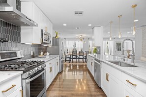 A modern kitchen with white cabinetry, stainless steel appliances, and a central island. - Relaxed Luxury Pet Friendly Home w/ Pool & Backyard Lounge in San Antonio, Tx (San Antonio)