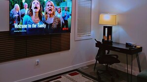 Un salon avec un téléviseur à écran plat fixé au mur, sur lequel est affiché le message : « Bienvenue dans la famille ».