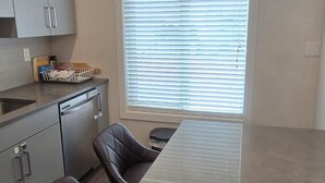 Une cuisine moderne dotée d’un îlot central, de tabourets de bar en cuir foncé et d’un luminaire suspendu.