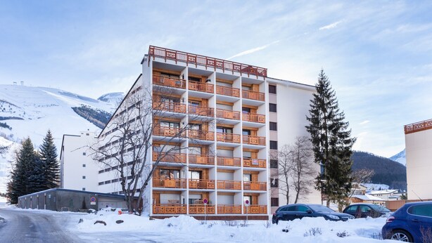 A multi-story hotel with balconies, a parking area, and snow-covered surroundings. - R Sidence Le Cabourg St4n (Les Deux Alpes)