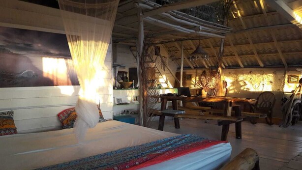 Ein Zimmer mit einem Bett, einer Sitzbank, einem Tisch und einem Hängesessel.