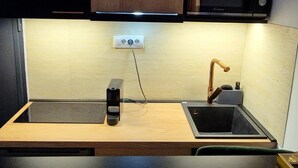 A modern kitchen with wooden cabinets, a built-in microwave, and a sink with a faucet. - Petit Palace (Beograd)