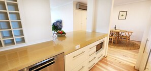 Eine moderne Küche mit integriertem Geschirrspüler, Obstschale und Essbereich mit Holztisch und Stühlen.