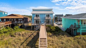 A beachfront property with a wooden walkway leading to a two-story building with balconies. - Oceanfront Holden Beach - 3BR, Private Pool, Sleeps 10 (Holden Beach)