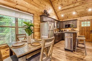 A wooden cabin interior with a dining table, chairs, a refrigerator, a microwave, and a sink. - Mountain Views, Hot Tub, Game Room & Deck (Sevierville)
