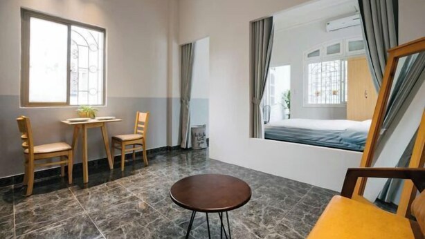 A hotel room with a bed, a small table, two chairs, and a round table. - Yuki Hanoi Center Apartment (Hanoi)