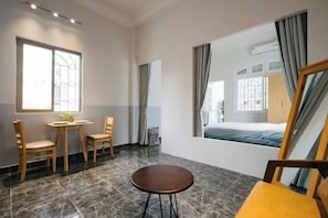 Une pièce avec un lit, une fenêtre, une table et deux chaises.