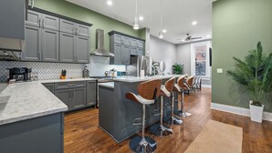 A modern kitchen with grey cabinets, a central island with bar stools, and a wooden floor. - Over-the-Rhine, 4 Bedroom, Game Room, Grill & Patio (Cincinnati)
