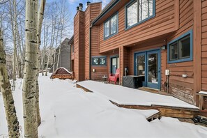 A wooden cabin with a covered porch, a red chair, and a stack of firewood. - Rivera's Run: Dog Friendly Frisco Townhome, Gas Fireplace, Walk to Downtown (Frisco)
