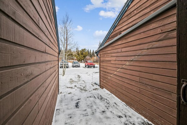 En smal trägång leder fram till ett garage där två bilar står parkerade utanför.