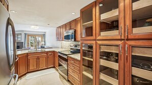 Eine Küche mit Holzausstattung, einem Edelstahlkühlschrank und einem eingebauten Backofen.