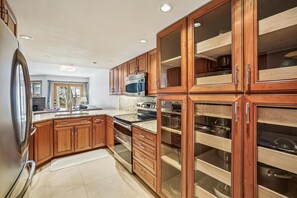 A kitchen with wooden cabinets, a stainless steel refrigerator, and a built-in oven. - Rivera's Run: Dog Friendly Frisco Townhome, Gas Fireplace, Walk to Downtown (Frisco)