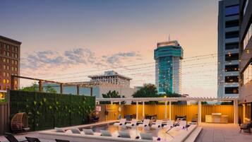 A rooftop pool area with lounge chairs, a small pool, and a pergola.