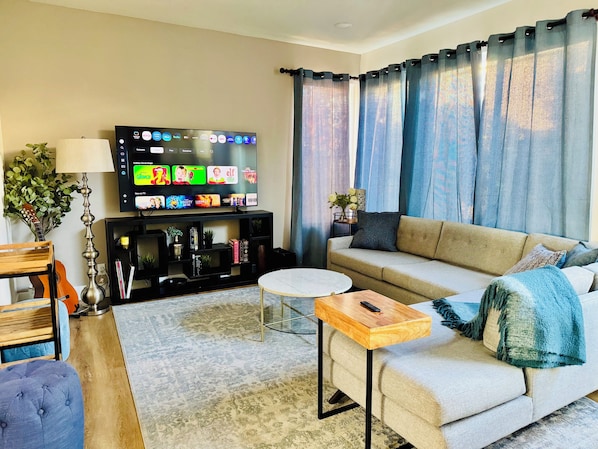 A living room with a flat-screen TV, a sofa, a coffee table, and a lamp.